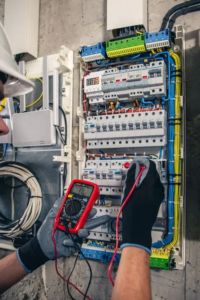 électricien travaillant sur un tableau électrique avec un voltmètre